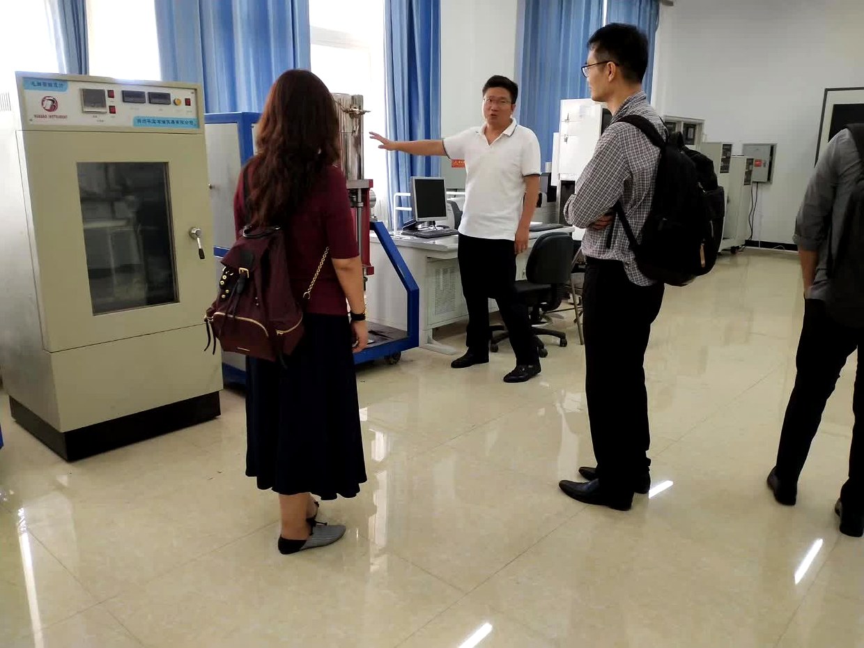 参观辽河油田研究院实验室，讲解人员在实验装置前向参观人员介绍设备