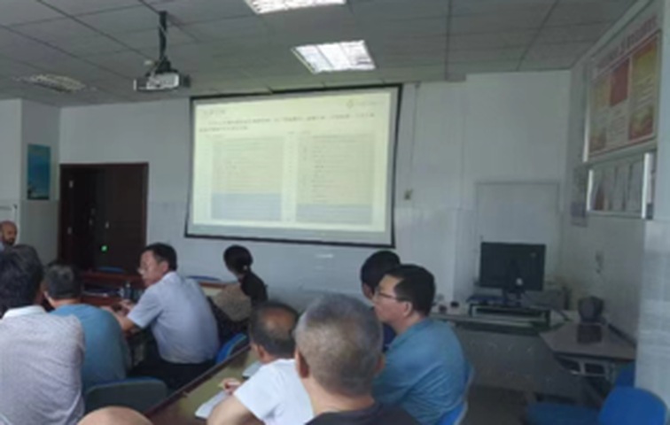 技术交流现场技术人员结合投影课件讲解，与会人员分排就座