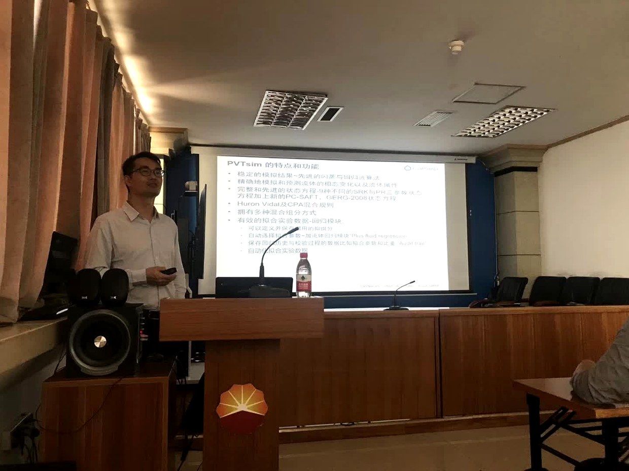 塔里木站交流现场，讲解人员在讲台旁，投影屏幕显示 PVTsim 的特点和功能